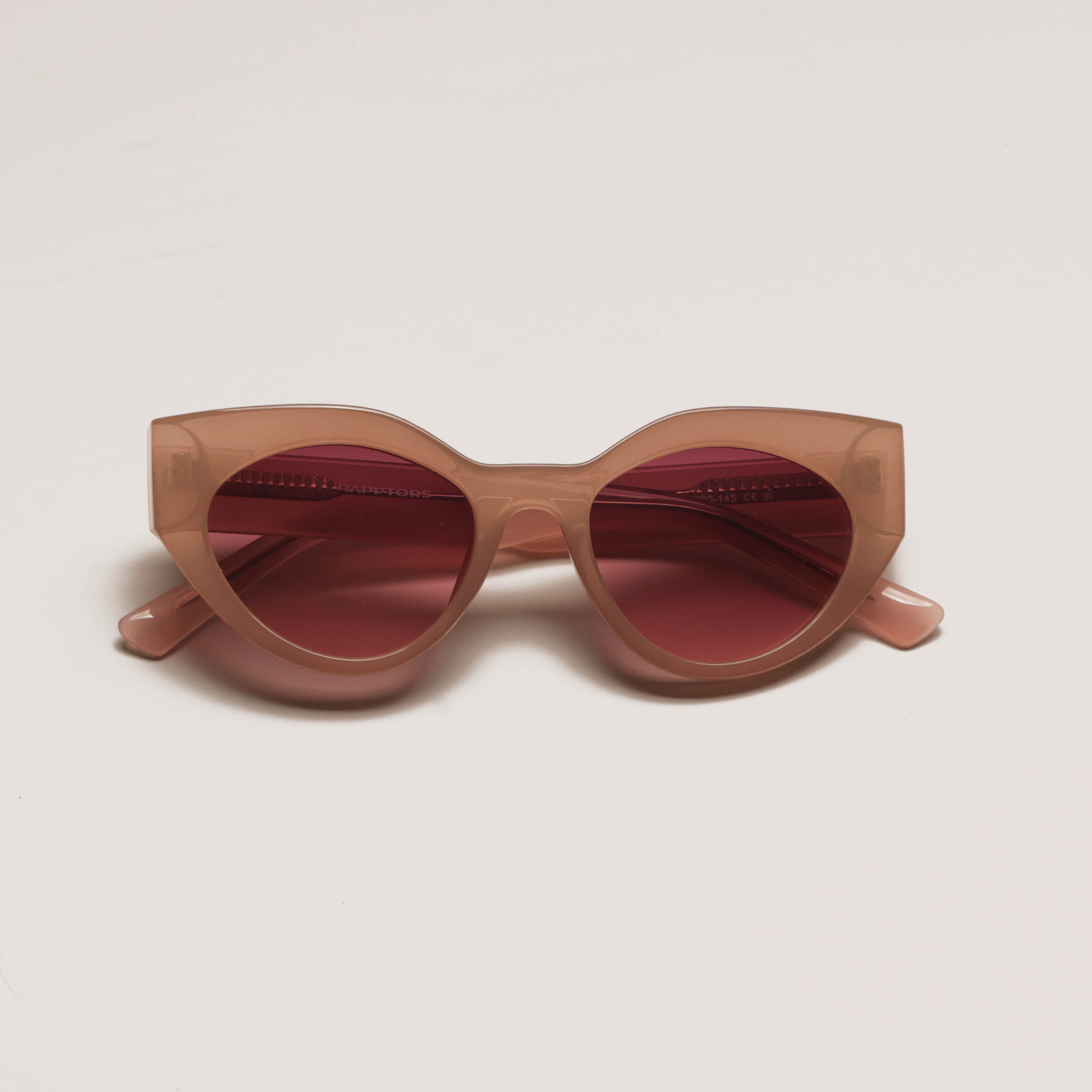 Sunglasses with a heart-shaped frame and red lenses on a beige background