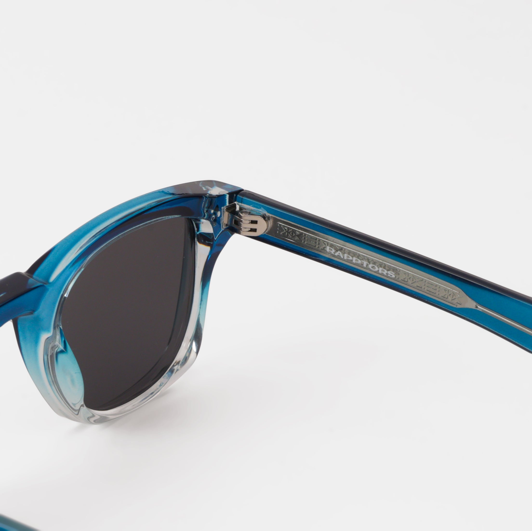 Close-up of a blue sunglasses with a visible brand logo on a white background